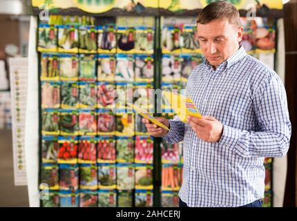 Ritratto di sorridere lieto amichevole maschio acquirente di scegliere le sementi per la semina in giardino Foto Stock