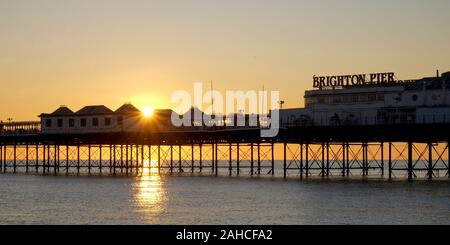 Brighton Palace Pier, la parte anteriore del molo con il nome su di esso, guardando dal mare, il sole tramonta sotto il molo formando una bella stella ef burst Foto Stock