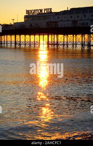 Brighton Palace Pier, la parte anteriore del molo con il nome su di esso, guardando dal mare, il sole tramonta sotto il molo formando una bella stella ef burst Foto Stock