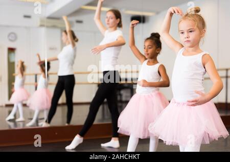 Giovani femmine di danza classica con insegnante aiutandola bambine gli studenti nella classe di balletto Foto Stock