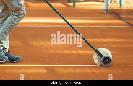 Pulizia di linee su un campo da tennis in terra battuta. Foto Stock