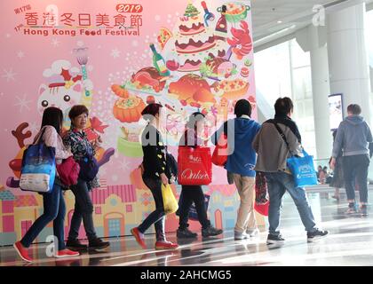 Hong Kong, Cina. 28 dicembre, 2019. I turisti a piedi passato un poster del XVII Hong Kong Food Festival a Hong Kong, Cina del sud, Dic 28, 2019. Credito: Wu Xiaochu/Xinhua/Alamy Live News Foto Stock