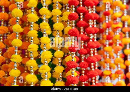 Appendere colorate decorazioni indiano in vendita nei colori del giallo, arancione e rosso nel vecchio mercato di Delhi in India Foto Stock