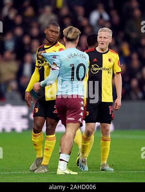 Watford Christian Kabasele (sinistra) tira su Aston Villa di Jack Grealish (centro) shirt al fianco di team-mate sarà Hughes (a destra) durante il match di Premier League a Vicarage Road, Watford. Foto Stock