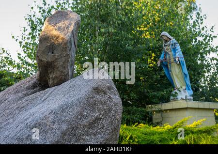 Enormi massi e la figura della Vergine Maria nel giardino Foto Stock