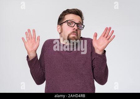 Dubbio giovane uomo in bicchieri gesti con le mani per negare a partecipare al vostro business. Foto Stock