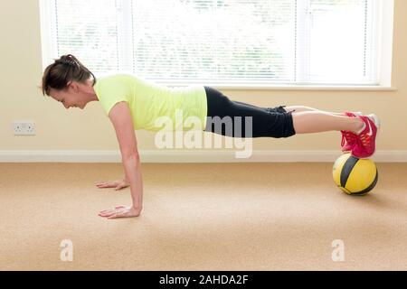 Donna facendo spingere ups tramite la medicina palla ginnica Foto Stock