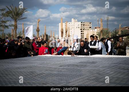 Giza in Egitto. 28 dicembre, 2019. Persone mettere tazze da caffè per creare un mosaico di antichi Egiziani re Tutankhamon maschera di Giza in Egitto il 28 dicembre, 2019. Presso il cantiere del Grand Museo Egizio (GEM) vicino le Grandi Piramidi di Giza in Egitto celebrata sabato in un open-air cerimonia impostando un nuovo Guinness World Record per il più grande mosaico di antichi Egiziani re Tutankhamon la maschera fatta di tazze da caffè. Credito: Wu Huiwo/Xinhua/Alamy Live News Foto Stock