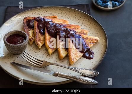 French toast con marmellata di mirtilli sul cemento grigio Sfondo. Messa a fuoco selettiva. Foto Stock