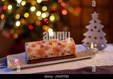 Yule log albo torta per Natale decorate con magnifici disegni con un colorato sfondo bokeh di fondo. Foto Stock