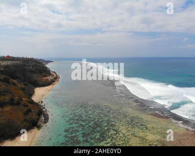 Vista aerea del blu oceano trasparente sulla costa sabbiosa con cliff. Le onde per il surf. Bali. Indonesia, meta di vacanza Foto Stock