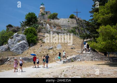 I turisti camminano lungo il sentiero fino al faro della Fortezza Vecchia, Corfù, Grecia Foto Stock