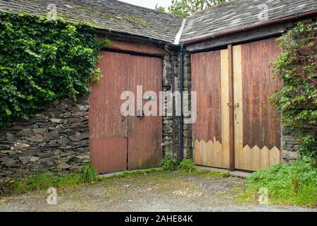 Porte in legno marrone di un fienile in pietra in una fattoria nel Lake District, Regno Unito Foto Stock