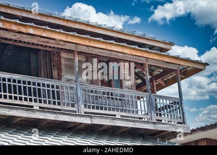 Questa foto unica mostra una vecchia casa di legno abbandonata con un bel cielo nuvoloso blu Foto Stock