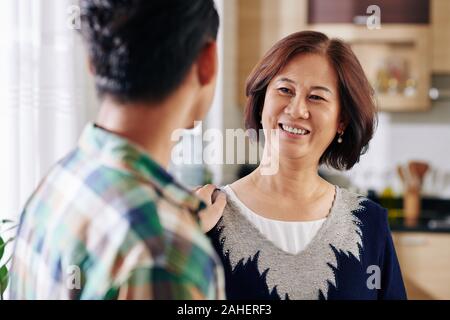 Sorridendo felice donna matura guardando suo Figlio raccontando buone notizie Foto Stock