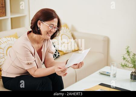 Felice di mezza età donna asiatica guardando le vecchie foto e ricordare vecchi tempi Foto Stock