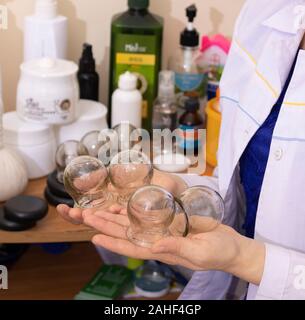 Close-up di un terapeuta mantenere il vuoto coppettazione trattamento per la schiena Foto Stock