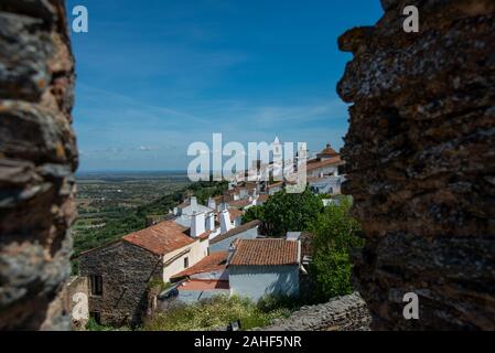 Blick von oben durch eine Maueröffnung auf die Ortschaft Monsaraz und die Landschaft Mit einem leicht bewölkten Himmel Foto Stock