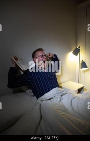 Uomo negli anni trenta che s'impegna nel "sonno pigmentato". Svegliarsi per un'ora di notte è stato sostenuto essere umano stato naturale. Foto Stock