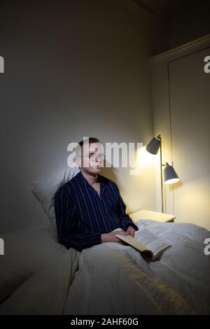 Uomo negli anni trenta che s'impegna nel "sonno pigmentato". Svegliarsi per un'ora di notte è stato sostenuto essere umano stato naturale. Foto Stock