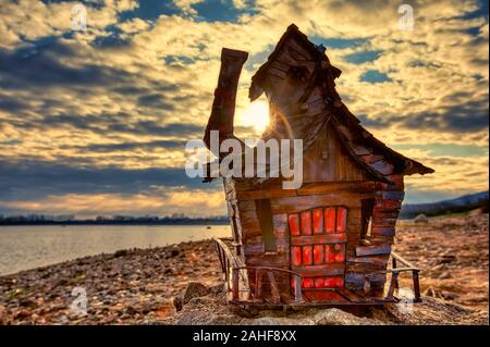 Fatte a mano in legno antico in miniatura della casa di montagna dal lago al sunrise. shallow DOF Foto Stock