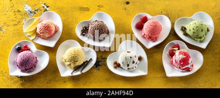 A forma di cuore piatti con un assortimento di gelati sapori e ingredienti freschi visto elevato angolo di legno in un panorama banner Foto Stock