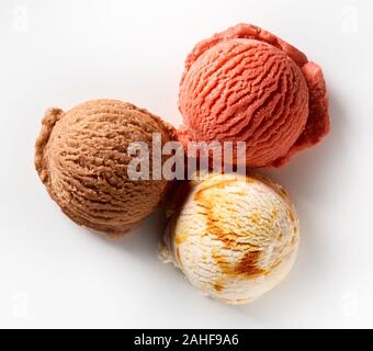 Tre differenti aromatizzati scoop di crema gelato con cioccolato berry e roteato caramello visto dall'alto verso il basso sul bianco per il menu pubblicità Foto Stock