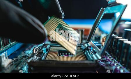 Ingegnere repairman tenendo le mani in guanti neri chip processore, CPU da inserire nella presa della scheda madre del computer. Il concetto di tecnologia Foto Stock