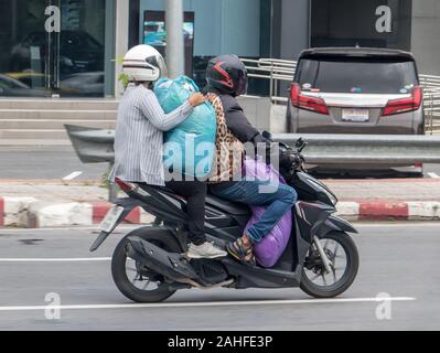 Giovane sulla moto che trasportano i sacchi di grandi dimensioni. Trasporto di invii di grandi dimensioni su un ciclomotore in città. Foto Stock