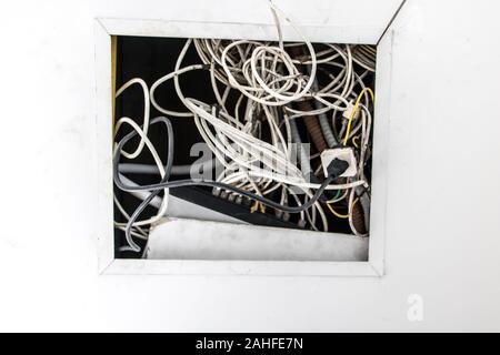 L'installazione elettrica, fili stick fuori del buco nel soffitto costruzione. Un groviglio di fili di comunicazione da appendere un foro nel soffitto. Foto Stock