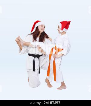 Famiglia sportiva in cappelli di Babbo Natale sono la formazione di kick gamba Foto Stock