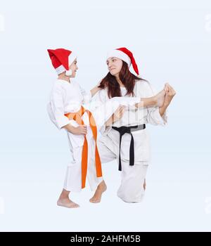 Con nero e arancio cintura in cappelli di Babbo Natale sport famiglia sono la formazione di kick gamba Foto Stock