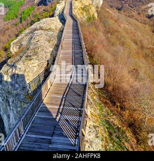Bella vista con ponte di legno che conduce attraverso un paesaggio autunnale all'orizzonte Foto Stock