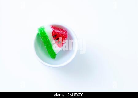 Anguria a forma di fetta gelatine in una piccola tazza bianca (vista dall'alto) Foto Stock