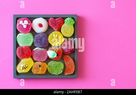 A forma di frutta gelatine in un vassoio quadrato, vista dall'alto (sfondo rosa) Foto Stock