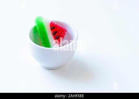 Anguria a forma di fetta gelatine in una piccola tazza bianca (vista frontale) Foto Stock