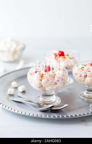 Una vista ravvicinata di piatti di insalata di Ambrosia su un metallo che serve il vassoio con una piccola ciotola di marshmallows in miniatura in dietro. Foto Stock