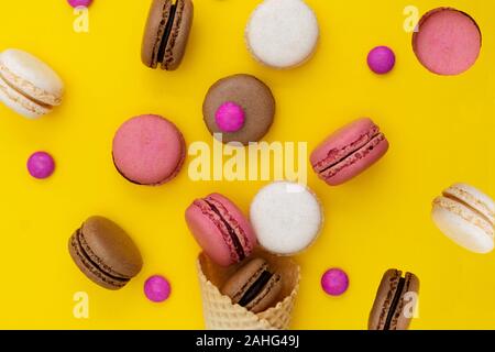Macarons dolci. Stil life foto del cono di cialda con amaretti su sfondo giallo. Lay piatto, dessert cibo. Foto Stock