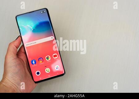 Corby, Regno Unito. Dicembre 25, 2019 - Samsung Galaxy S10 telefono cellulare, mano azienda S10 di bianco su sfondo blu. Editoriale illustrativa Foto Stock