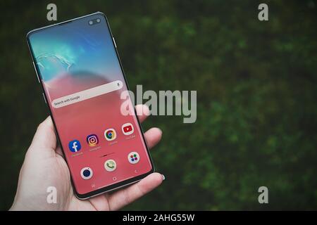 Corby, Regno Unito. Dicembre 25, 2019 - Samsung Galaxy S10 telefono cellulare, mano azienda S10 di bianco su sfondo blu. Editoriale illustrativa Foto Stock