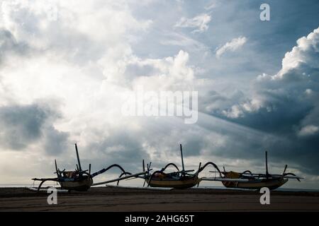 Cielo infinito con cumulus nubi. Il sorgere del sole sul mare. Barche da pesca sulla sabbia costiera. I raggi del sole splendidamente rompere attraverso le nuvole mi Foto Stock