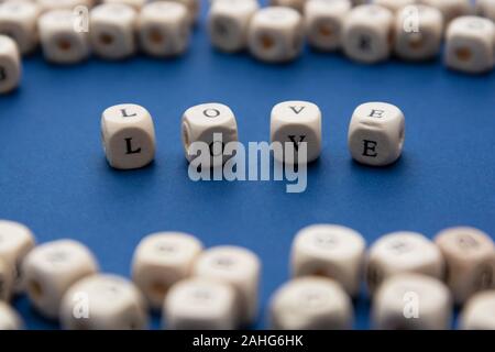 L amore è amore messaggio scritto su blocchi di legno su sfondo blu, vista dall'alto. Foto Stock