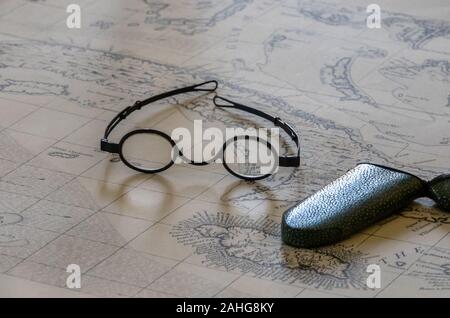 Coppia di round occhiali con lenti di ingrandimento sulla parte superiore del vecchio polso mare mappa Foto Stock