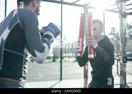 Calma boxing trainer tenendo il pugilato bastoni e guardando attento Foto Stock