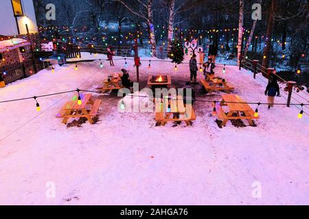 Sala da pranzo all'aperto nella neve con un falò e parco di legno panche di Leavenworth, nello Stato di Washington, USA in una fredda notte d'inverno. Foto Stock