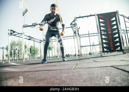 Barbuto tiro sportivo di corde elastiche mentre la formazione i suoi muscoli Foto Stock