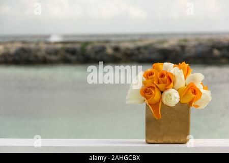 Allestimento per matrimoni, secchiello con fiori bianchi e arancioni sulla spiaggia. Speciale cerimonia di celebrazione del concetto di mare Foto Stock