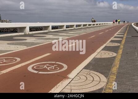 Piste rosse in bicicletta accanto al marciapiede pedonale sulla costa di Las Palmas, Spagna. Attività all'aperto, ambiente sano, interesse verde, inquinamento Foto Stock