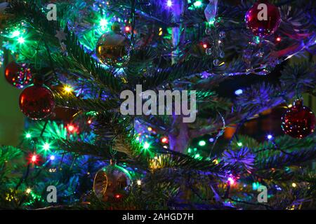 Close-up di una parte di un albero di Natale con decorazioni di Natale, baubles tinsel, stelle e le luci fairy, Haslemere, Surrey, Regno Unito. Foto Stock
