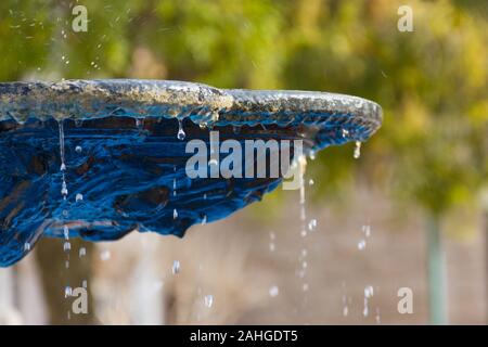 Primo piano sulla fontana d'acqua con la figura sul fondo e gocce che cadono e schizzi Foto Stock